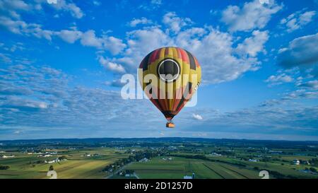 Aerial view of blue sky and multiple clouds and a hot air balloon floating thru it Stock Photo