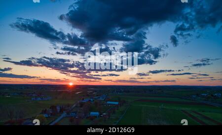 Aerial view of a Sunset over barns, silos and farmlands during the ...