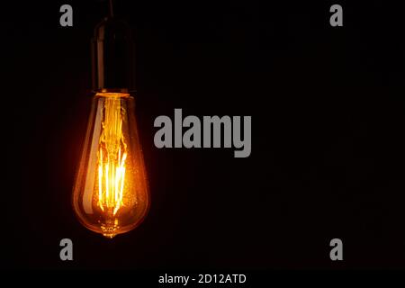 Vintage light bulb on black background with copy space. Glowing edison bulb Stock Photo