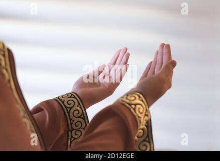 Islamic Dua Concept. Female hands.Peaceful spiritual moments. Hand raised up for praying to Allah.Hand of Muslim people praying with mosque interior b Stock Photo