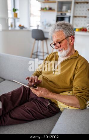 Technology, people and lifestyle concept. Senior man with tablet pc computer relaxing at home Stock Photo