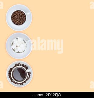 Three cups on saucers with sugar cubes, coffee and coffee beans on a beige background. Free space for text. The view from the top. Stock Photo