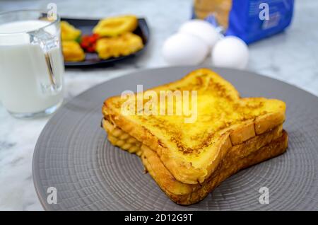 Beautifully Stacked French Toast in a plate along with milk, eggs, bread packet Stock Photo