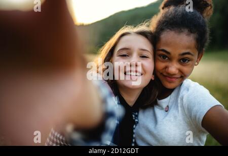 Front view of young teenager girls friends outdoors in nature, taking selfie. Stock Photo