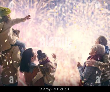 New Year holiday. Parents and daughters children girls are watching fireworks. Happy family on snowy winter walk in nature. Holidays winter season. Stock Photo