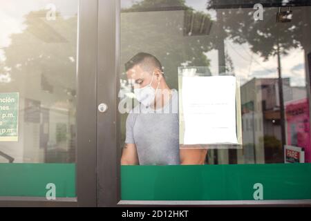 A closeup shot of a male opening a closed-door wearing a sanitary mask - concept of the new normal Stock Photo