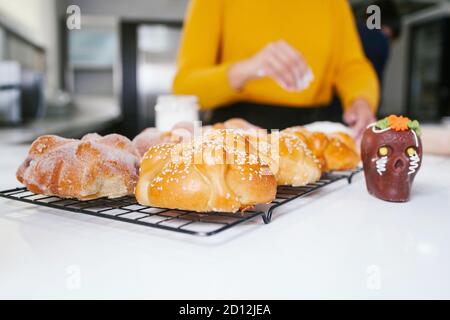 Mexican woman baking Pan de Muerto traditional bread from Mexico in Halloween Stock Photo