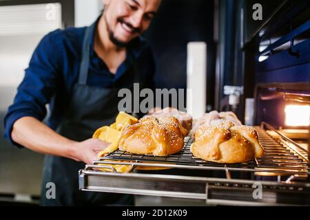 Mexican man baking bread called pan de muerto traditional from Mexico in Halloween Stock Photo