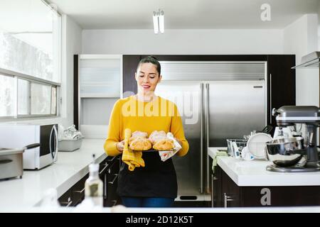 Mexican woman baking Pan de Muerto traditional bread from Mexico in Halloween Stock Photo