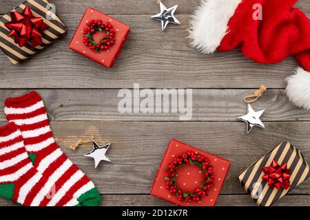 Red Santa hat, gift boxes and socks on old wooden background Stock Photo