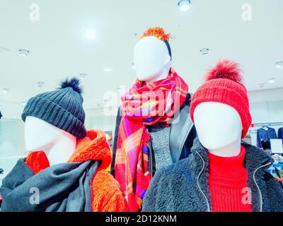 Three faceless mannequins in warm clothes in a store with a white ceiling and many lamps Stock Photo