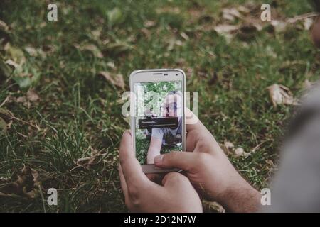 Male lying on the grass and taking a selfie of him and his girlfriend holding a camera Stock Photo