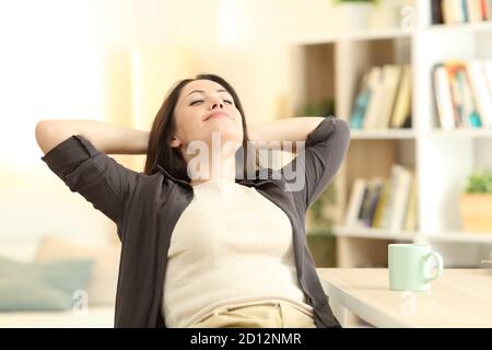 Relaxed satisfied woman sitting on a chair in the living room at home Stock Photo