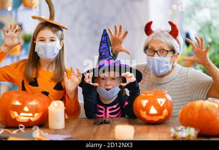 Happy family celebrating Halloween. Grandmother and children wearing face masks protecting from COVID-19. Stock Photo