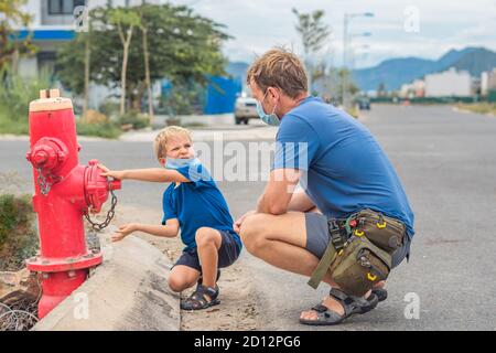 Father influence son worldview family education study everyday knowledge skills. Dad in blue COVID face mask show tell teach child fireman fighters Stock Photo