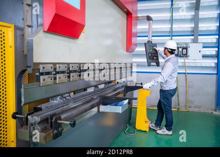Asian technician worker wearing a safety suit Setting Hydraulic Press Break Machine and Prepared Sheet Metal Shearing in industrial factory, Safety fi Stock Photo