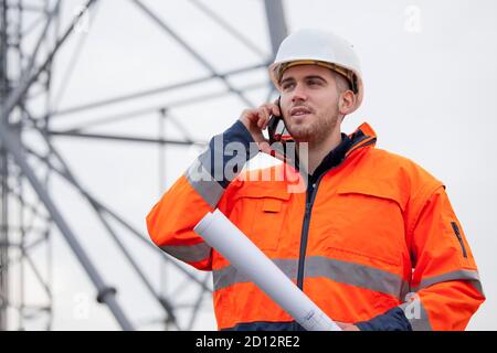 Young engineer or foreman talking  on smart phone on a oil platform or construction site - selective focus Stock Photo