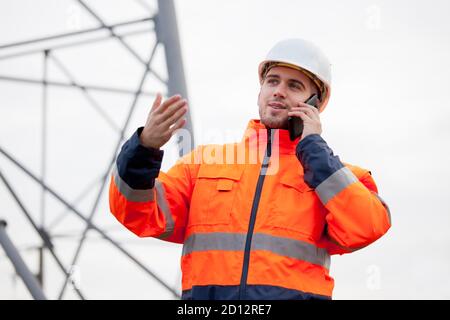 Young engineer or foreman talking  on smart phone on a oil platform or construction site - selective focus Stock Photo