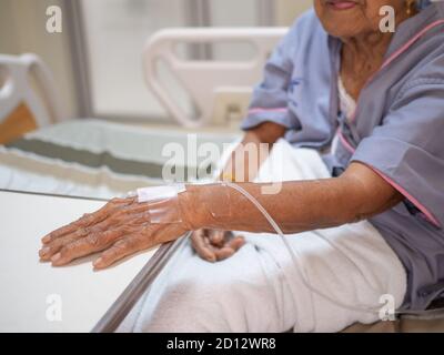 Saline solution drip on old women hand in hospital. Health care and Medical equipment concept. Stock Photo