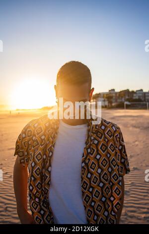 Young man sunset portrait. Sunset in background. Vertical view.