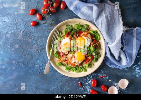 Traditional Israeli Cuisine dishes Shakshuka. Fried egg with vegetables tomatoes and paprika in ceramic plate with cloth, herbs and ingredients above Stock Photo