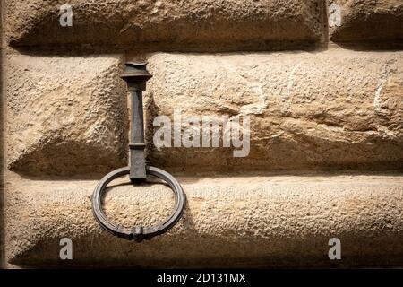 Ancient wrought iron ring for tying with rope the animals, horses, mules or cattle, on a stone wall (ashlar). Florence downtown, Tuscany, Italy. Stock Photo
