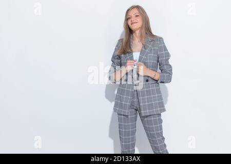 Positive fashion businesswoman smiling and joking about being tough while standing on white studio background Stock Photo