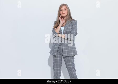 Confident fashion businesswoman holding hands on neck and wearing suit while standing on white studio background Stock Photo