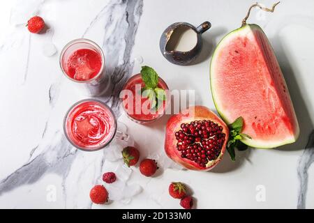 Three different red fruit berry watermelon, strawberry, raspberry, pomegranate cocktails or smoothies in glasses with crushed ice, fresh mint, ingredi Stock Photo