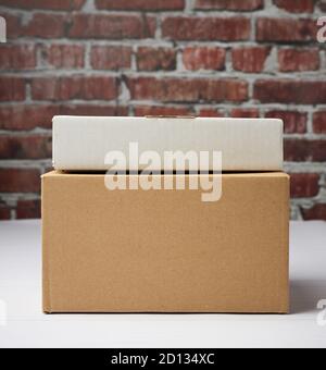 rectangular box made of brown corrugated cardboard on a brown brick wall background, close up Stock Photo