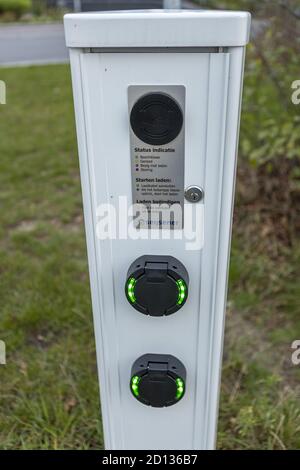 HOGE HEXEL, NETHERLANDS - Aug 30, 2020: Charging pole with instructions in Dutch and cable outlets on a parking lot Stock Photo
