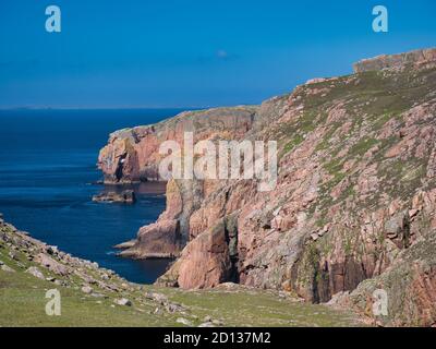 Red granite cliffs on Muckle Roe, Shetland, UK - these rocks are of the Muckle Roe Intrusion - granite, granophyric - igneous bedrock formed 359 to 38 Stock Photo