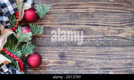 Christmas background with holiday trimmings of pine tree branches, ornaments, black and white buffalo check ribbon, burlap and red bead garland.. Top Stock Photo