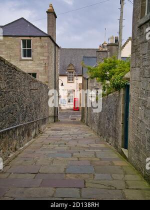 A view down the pedestrian, stone flagged Queens Lane to Commercial Street in the town centre of Lerwick, capital of Shetland, Scotland, UK. Stock Photo