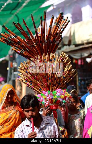 A man selling flutes and plastic toys displayed on his shoulder on the streets of Pushkar, Rajasthan, India on 10 November 2018 Stock Photo