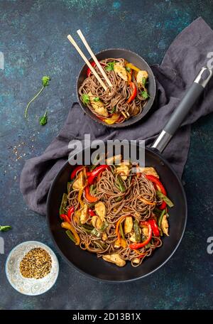 Japanese dish buckwheat soba noodles with chicken and vegetables carrot, bell pepper and green beans in wok on dark blue background Stock Photo