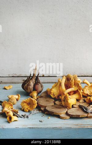 Raw uncooked Chanterelles forest mushrooms on blue white wooden kitchen table with garlic and knife. Rustic style, day light, copy space Stock Photo