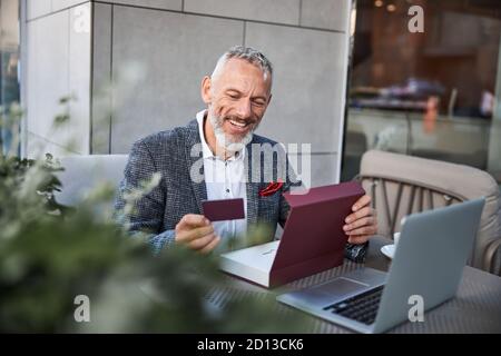Gladsome senior man holding a plastic card Stock Photo