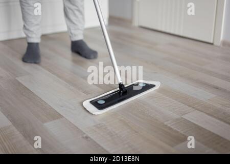 housekeeping concept - close up of cleaning wooden parquet floor with mop Stock Photo