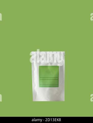 Aluminum bag for tea, coffee, condiments and other bulk substances with green label for signature on green background.  Stock Photo