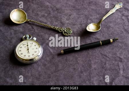 Vintage pocket clock, fountain pen and spoons on the table Stock Photo