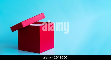 Empty pink gift box with ajar lid on light blue background. Holidays concept. Copy space. Banner. Mockup for branding Stock Photo