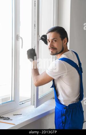 Handyman in work clothes preparing to install a window Stock Photo