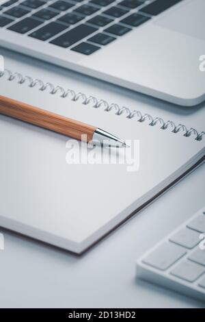 Closeup shot of brown pen with notebook and laptop on workspace. Stock Photo