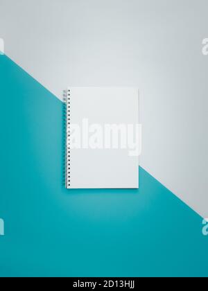 Blank spiral notebook on white and cyan background Stock Photo