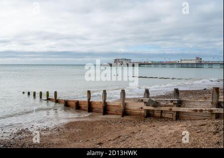 Looking west to Worthing Pier over the beach with wooden groynes spaced out to protect against sea erosion. West Sussex, UK. Stock Photo