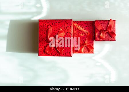 Three red gift boxes in different sizes isolated on blue background Stock Photo