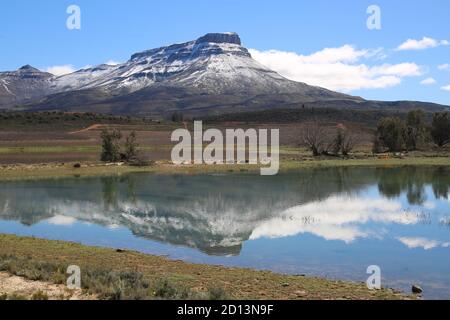 Snowcapped Koue Bokkeveld Mountains near Op-die-Berg reflecting in a dam on a clear day during winter Stock Photo