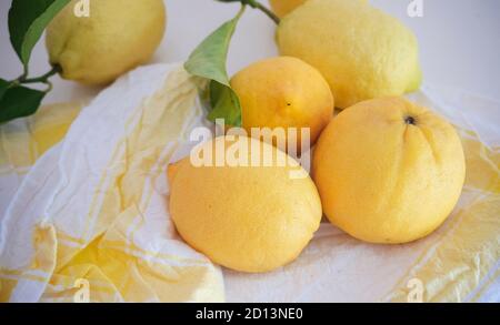 Fresh whole lemons with leaves on the white-yellow linen napkin Stock Photo
