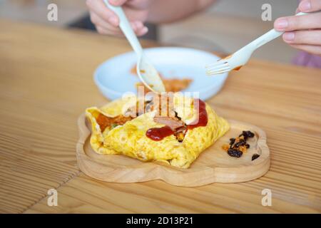 Omelette Wrapped with Pork and Stir-fried Sauce Placed on a wooden plate Stock Photo
